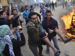 Dos personas trasladan a un hombre que result&oacute; herido durante los disturbios en Giza, cerca de El Cairo (Egipto).