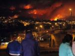 Cuatro personas observan c&oacute;mo un incendio forestal arrasa con zonas urbanas en la ciudad de Valpara&iacute;so, Chile.