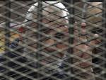 El l&iacute;der de los Hermanos Musulmanes, Mohamed Badie, hace la se&ntilde;al de los cuatro dedos desde detr&aacute;s de unas rejas, durante un juicio en El Cairo, Egipto.