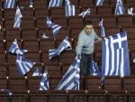 Un hombre coloca banderas griegas en un pabell&oacute;n.