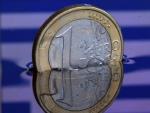 Fotograf&iacute;a ilustrativa de una moneda de 1 euro semisumergida en el agua, que a su vez refleja los colores de la bandera de Grecia.