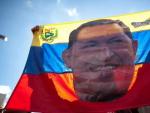 Un seguidor de Ch&aacute;vez sostiene una bandera venezonala con su cara en una manifestaci&oacute;n en Caracas.