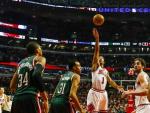 El jugador de Bulls Derrick Rose lanza hacia la cesta ante la marca de Giannis Antetokounmpo y John Henson