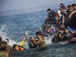 Varios hombres saltan al agua desde una lancha neum&aacute;tica tras alcanzar las costas de la isla griega de Lesbos.