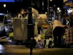 Un grupo de personas rebusca en un contenedor de basura en Madrid.