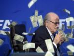 El presidente de la FIFA, Joseph Blatter, bajo una lluvia de billetes que le lanz&oacute; el humorista brit&aacute;nico Simon Brodkin, durante una rueda de prensa para presentar los resultados de la reuni&oacute;n del Comit&eacute; Ejecutivo de la FIFA en su sede de Z&uacute;rich, Suiza, en julio de 2015.