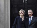 La nueva primera ministra brit&aacute;nica, Theresa May (i), y su marido Philip (d), saludan a los medios .
