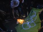 Manifestantes contra los Juegos Ol&iacute;mpicos R&iacute;o 2016 queman una bandera en la plaza Sans Pena en Tijuca, al norte de R&iacute;o de Janeiro (Brasil).