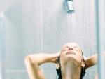 Una mujer se lava el pelo bajo el grifo de la ducha.