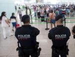 Agentes de los Mossos d'Esquadra controlan de los accesos a las puertas de embarque en el Aeropuerto de El Prat este s&aacute;bado.