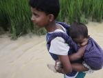 Un ni&ntilde;o rohiny&aacute; portea a su hermana peque&ntilde;a cruzando de Birmania a Bangladesh.