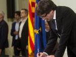 El presidente de la Generalitat, Carles Puigdemont, firma el documento sobre la Independencia despu&eacute;s de comparecer ante el pleno del Parlament para trasladar los resultados de la jornada del 1-O,