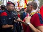 Un hombre con la bandera de Espa&ntilde;a saluda a un mosso de esquadra durante la manifestaci&oacute;n este mediod&iacute;a en Barcelona bajo el lema &quot;Catalu&ntilde;a s&iacute;, Espa&ntilde;a tambi&eacute;n&quot;, convocada por Societat Civil Catalana.