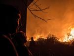 Unos vecinos observan como se acerca a sus casas el incendio forestal de Carballeda de Avia (Ourense).