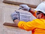 Un operario retira una placa franquista de una fachada de Barcelona.