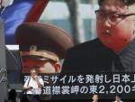 Los peatones caminan bajo un monitor a gran escala que muestra al l&iacute;der norcoreano Kim Jong-un en una emisi&oacute;n de noticias de televisi&oacute;n.