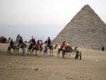 Varios turistas disfrutan de un paseo a camello delante de la Pir&aacute;mides en Guiza (Egipto).