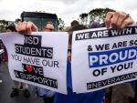 Estudiantes del instituto Marjory Stoneman Douglas reparten carteles mientras esperan al autob&uacute;s en Parkland, Florida.