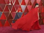 La actriz Sofia Carson hace volar su capa roja sobre la alfombra del mismo color, en la ceremonia de los &Oacute;scar 2018.