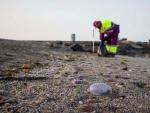 Un operario municipal recoge medusas en la orilla de la playa de El Zapillo