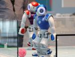 Dos robots juegan al f&uacute;tbol en el stand de German Federal Printing Office, durante la feria de tecnolog&iacute;a CeBIT, en Hannover (Alemania).