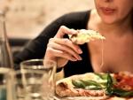 Una mujer come una porci&oacute;n de pizza.