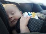 Un beb&eacute; duerme en la silla infantil de un coche.