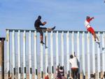 Integrantes de la caravana de centroamericanos escalan el muro fronterizo con EE UU en Tijuana, M&eacute;xico.