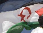 Un defensor del Frente Polisario pasa junto a una bandera del S&aacute;hara Occidental.