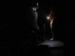 Dos personas se iluminan con sus tel&eacute;fonos m&oacute;viles ante la falta de suministro el&eacute;ctrico en la zona, en Caracas (Venezuela).