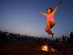 Una joven salta la hoguera que ha encendido junto a un grupo de amigos para celebrar la noche de San Juan, en la playa de la Malvarrosa de Valencia.