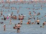 Un gran n&uacute;mero de personas se refresca en las aguas de la playa de la Malvarrosa de Valencia.