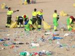 Operarios del ayuntamiento de Barcelona retirando basura de la playa de la Nova Ic&agrave;ria tras la verbena de Sant Joan.