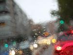 Una calle con retenciones por la lluvia, vista desde el interior de un coche con los cristales empapados.