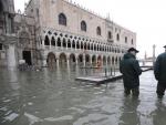 Dos personas caminan por la inundada plaza de San Marcos en Venecia.
