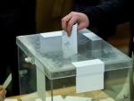 Un votante deposita un voto en una urna.