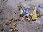 Playa contaminada por colillas de cigarrillos y residuos de pl&aacute;stico.