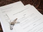Unas llaves sobre un contrato de compraventa de vivienda y un contrato de arrendamiento (alquiler) de una habitaci&oacute;n en una vivienda compartida.
