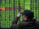 Un inversor burs&aacute;til se sienta frente a una pantalla de la Bolsa en Hangzhou, China,