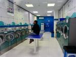 Un hombre observa la televisi&oacute;n en una lavander&iacute;a de Madrid, uno de los pocos negocios fuera de los esenciales que permanecen abiertos.