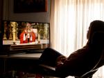 Una mujer sigue una misa televisada, durante el Domingo de Ramos, en su domicilio en Sevilla.