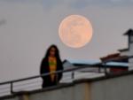 Una mujer pasea por una azotea durante la cuarentena por coronavirus en Roma, mientra la 'luna rosa' ilumina el cielo un 15% m&aacute;s fuerte.