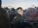 Un ni&ntilde;o sirio refugiado sonr&iacute;e en brazos de su madre en la frontera entre Eslovenia y Austria en noviembre de 2015
