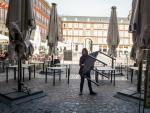 Varios empleados de un bar de la Plaza Mayor de Madrid recogen la terraza un d&iacute;a antes de que se cierre toda la hosteler&iacute;a