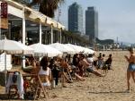 Varias personas disfrutan de un chiringuito en la playa de la Barceloneta.