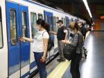 Varios pasajeros abren la puerta de un tren de Metro de Madrid.