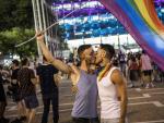 Una pareja de gais se da un beso, bajo una bandera arco&iacute;ris, durante una manifestaci&oacute;n por el 'Orgullo 2020', en Tel Aviv (Israel).