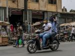 Dos hombres con mascarilla en una moto en Dakar.