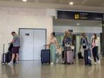 Varios turistas con mascarillas por el coronavirus llegan al aeropuerto de Menorca en un vuelo procedente de Londres.