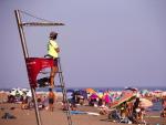 Un socorrista con mascarilla observa atentamente a los ba&ntilde;istas en la playa de la Malagueta de M&aacute;laga.